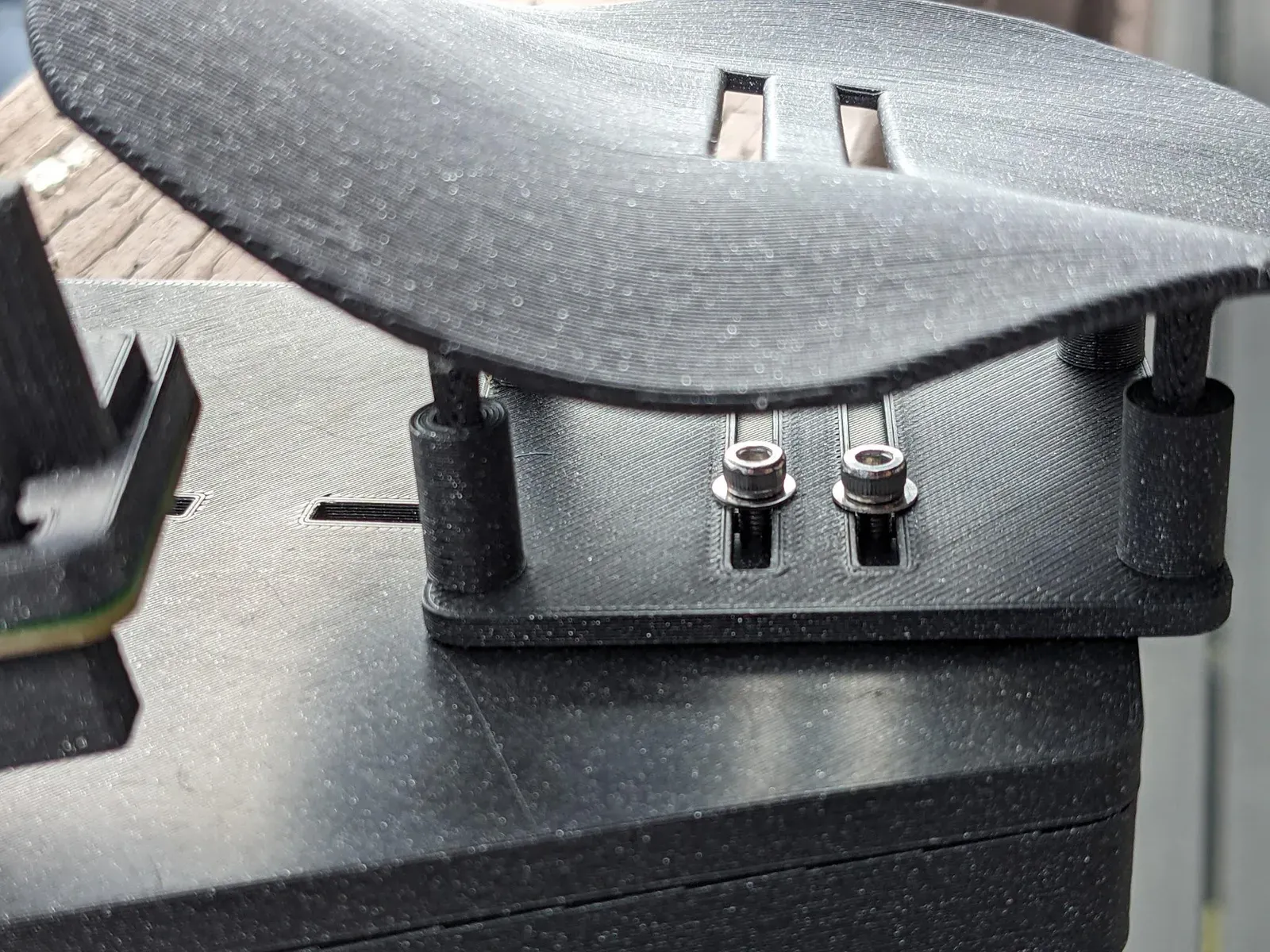 The palm rest carrier on the base plate, with its two screws in the carrier slots.
