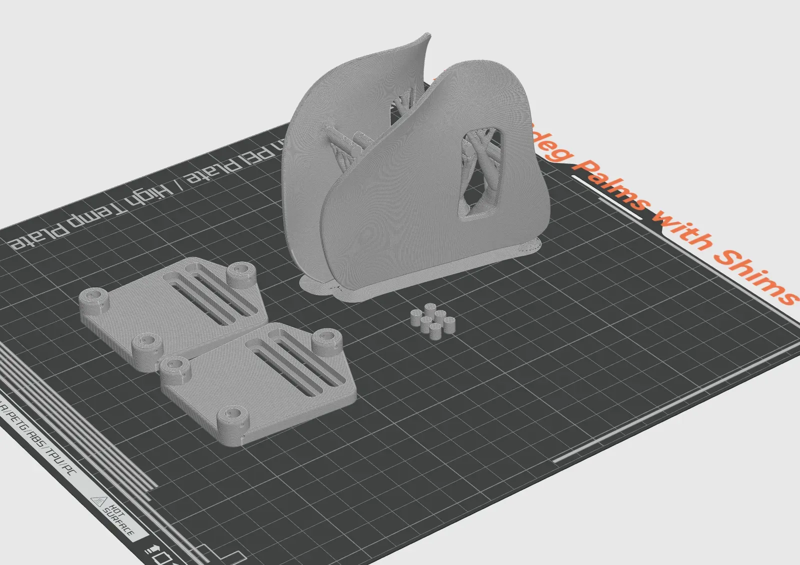 Slicer view of a palm rest standing on its long edge with tree supports, next to two carriers and a set of shims.
